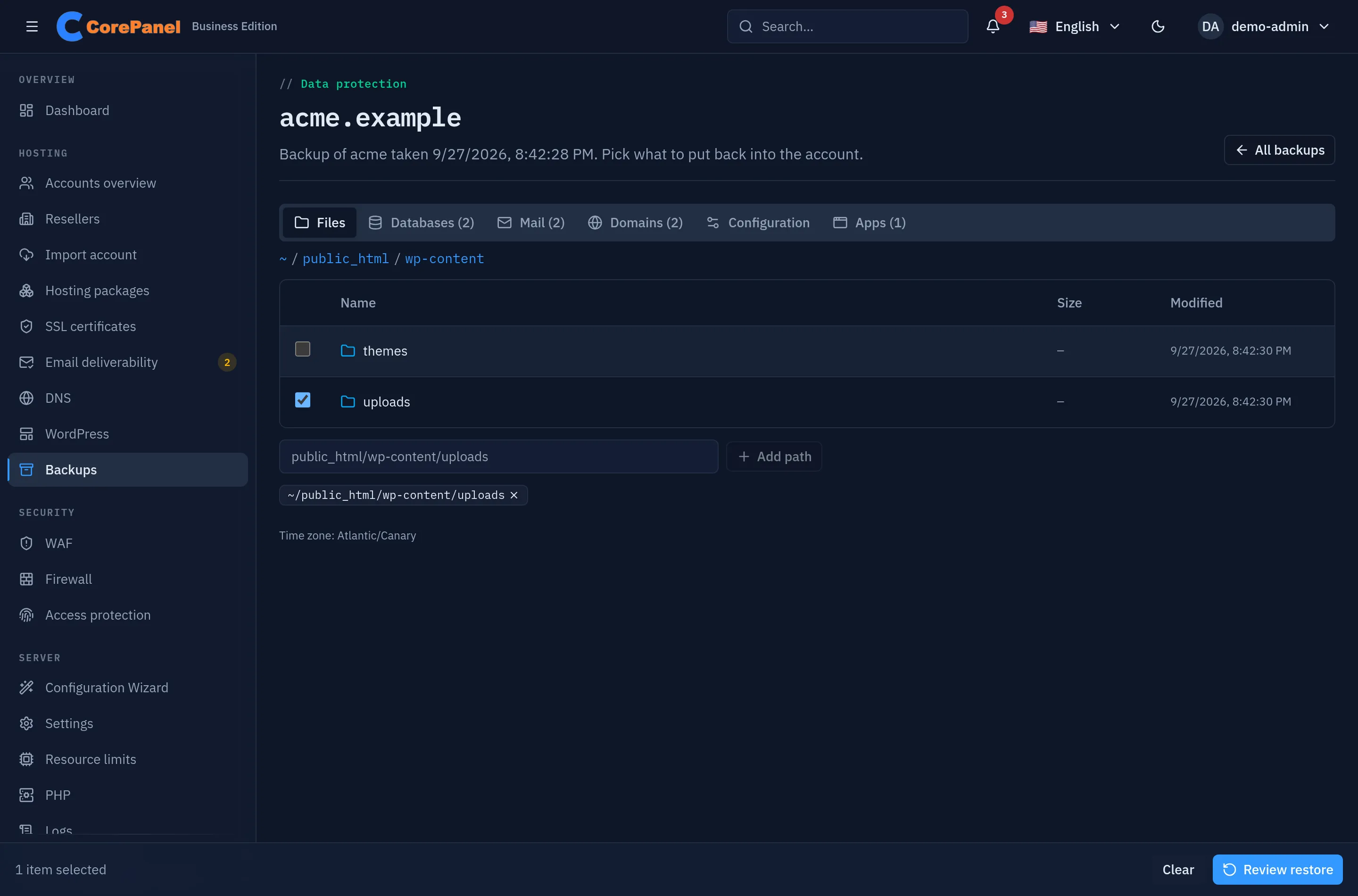 The backup browser for acme.example: tabs for Files, Databases, Mail, Domains, Configuration and Apps, the Files tab open at public_html/wp-content with the uploads folder ticked, a field to add a path by name, the selected path shown as a chip, and a bar at the bottom reading "1 item selected" with a Review restore button