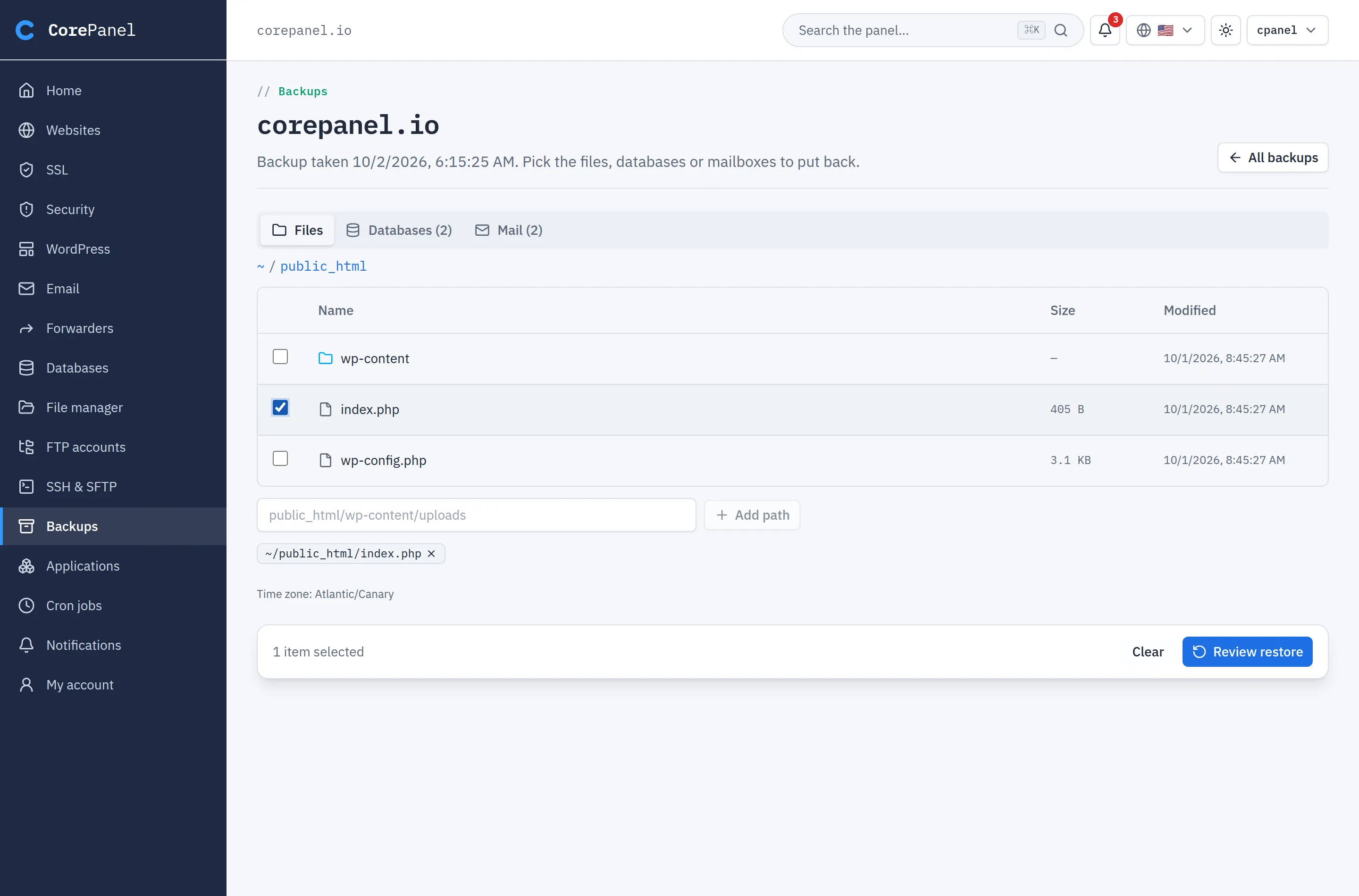 The client panel's backup browser for corepanel.io: the line "Backup taken 10/2/2026. Pick the files, databases or mailboxes to put back", tabs for Files, Databases (2) and Mail (2), the Files tab open at public_html with index.php ticked, the selected path shown as a chip, and a bar at the bottom reading "1 item selected" with a Review restore button